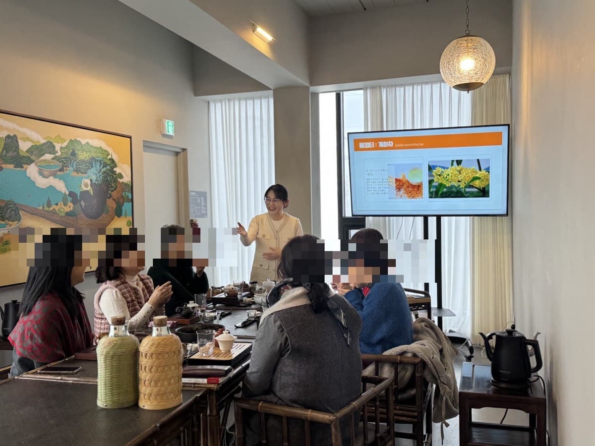 참가자들이 차를 마시며 진행자의 설명을 듣는 모습